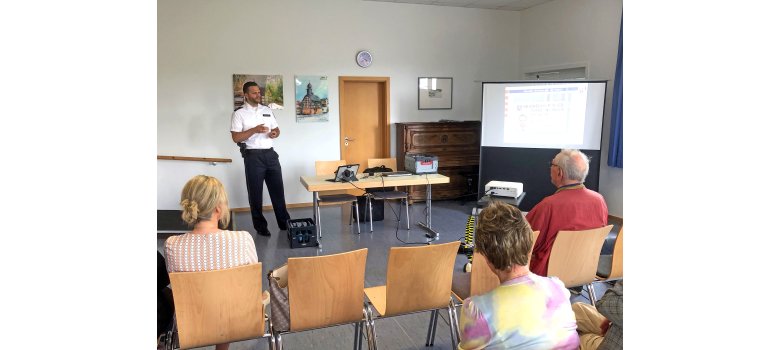 Ein Polizeibeamter steht vor einer Leinwand und hält einen Vortrag